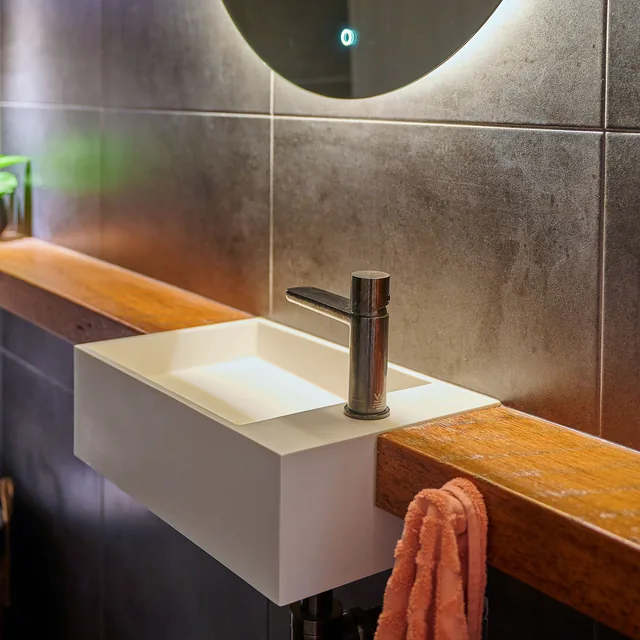 A rectangular basin sitting on a solid timber ledge, with a single wall-mounted mixer above it.