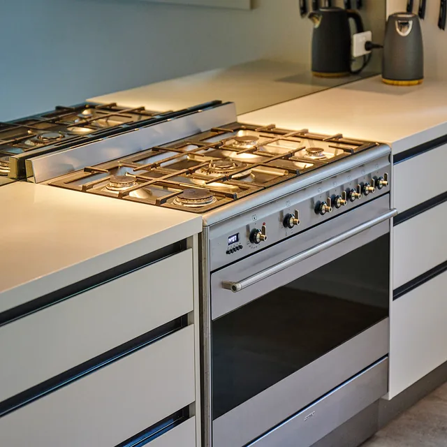 A gas cooktop set into a stone benchtop above an oven.
